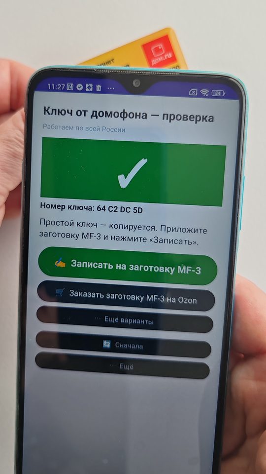 Ключ приложен к задней стенке телефона у верхнего края, на экране приложения зелёный вердикт: простой ключ